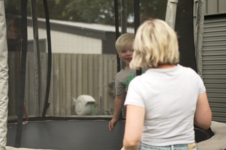 Kara van der Walt watches her son Kobe play on a trampoline.