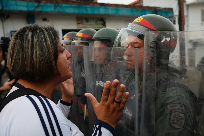 A female demonstrator squares up to a soldier in riot gear near the Venezuelan border with Colombia.