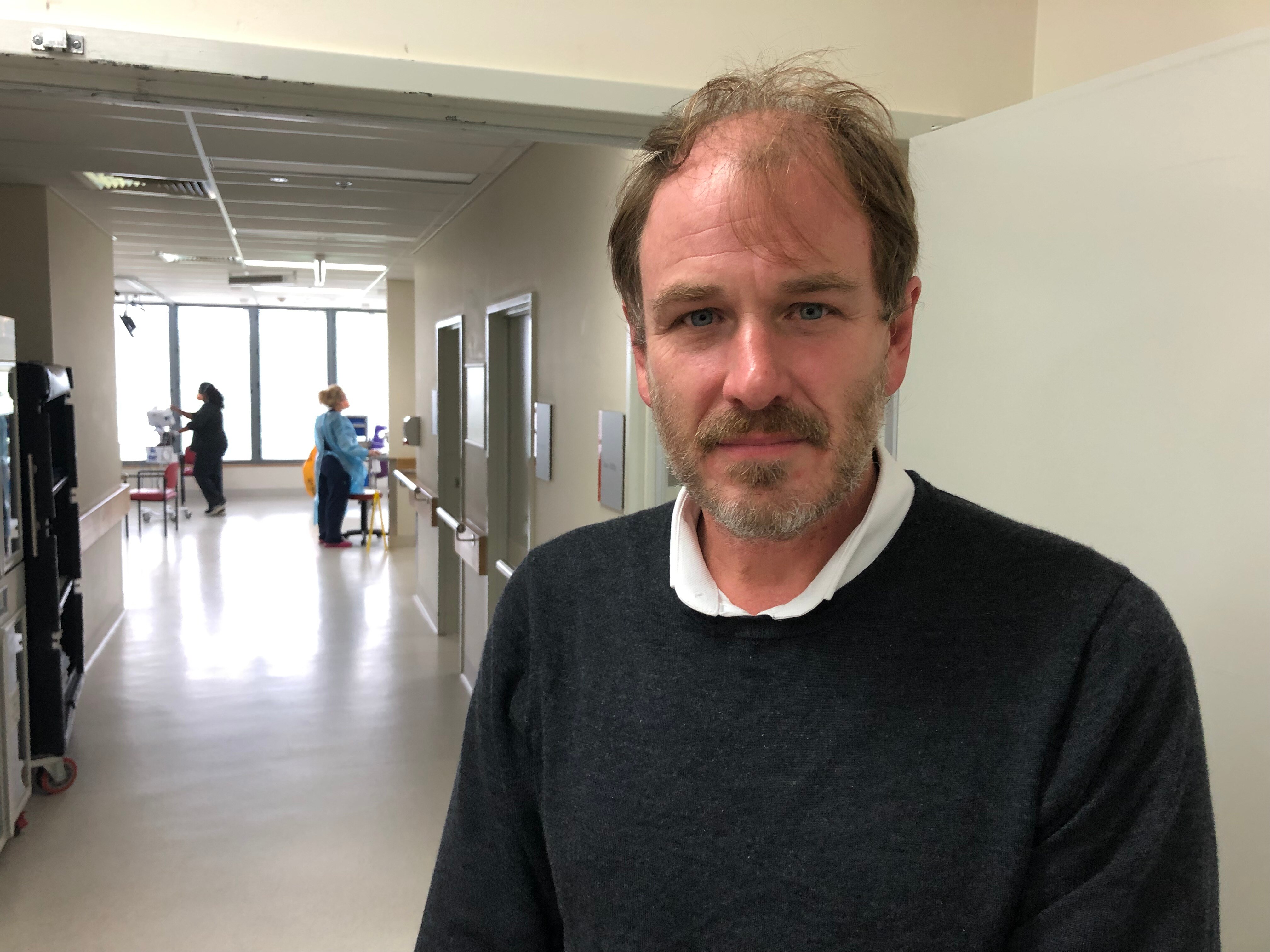 Dr Geoffrey Playford stands in a hospital corridor.