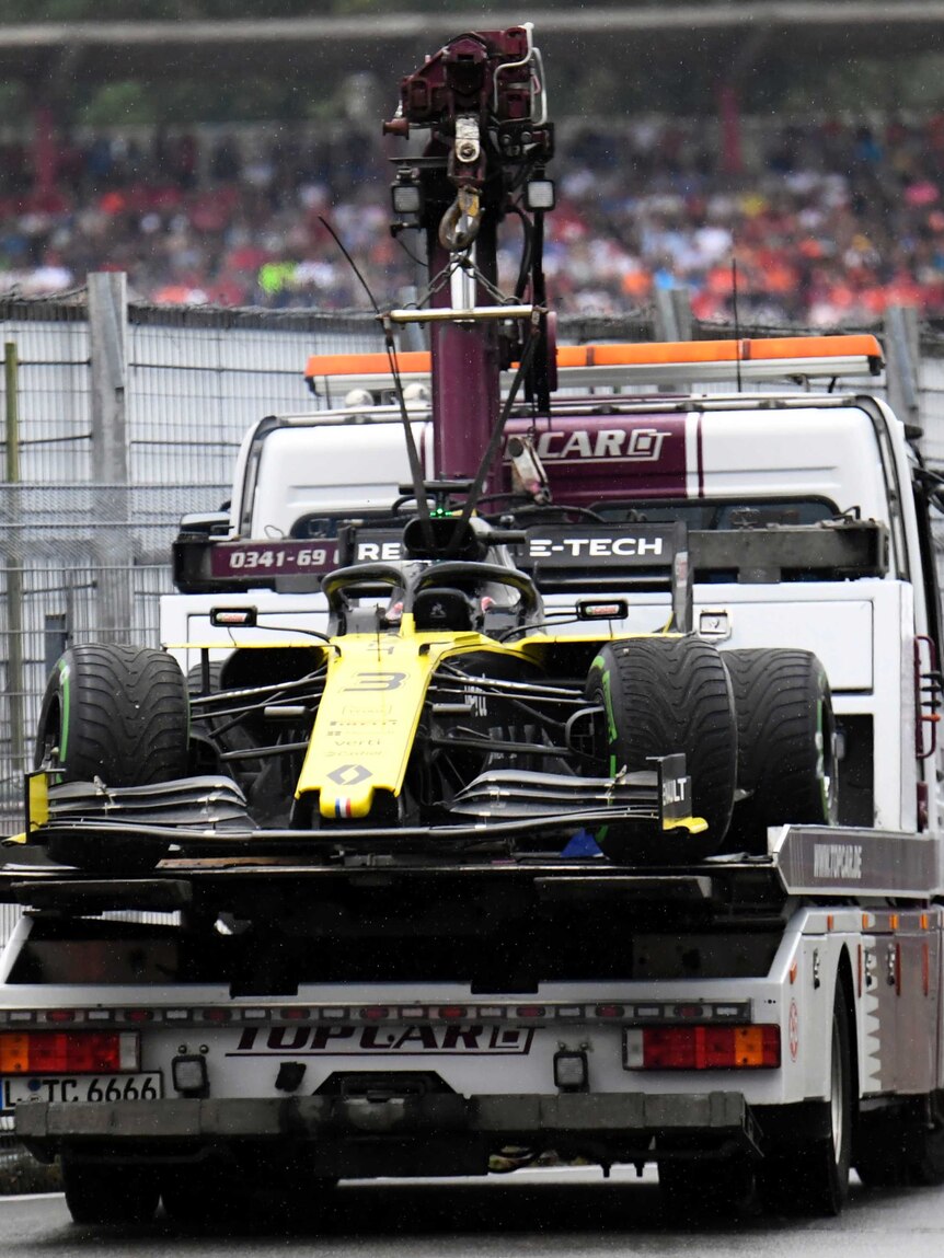 An F1 car sits on the back of a truck during a grand prix race after failing to finish.