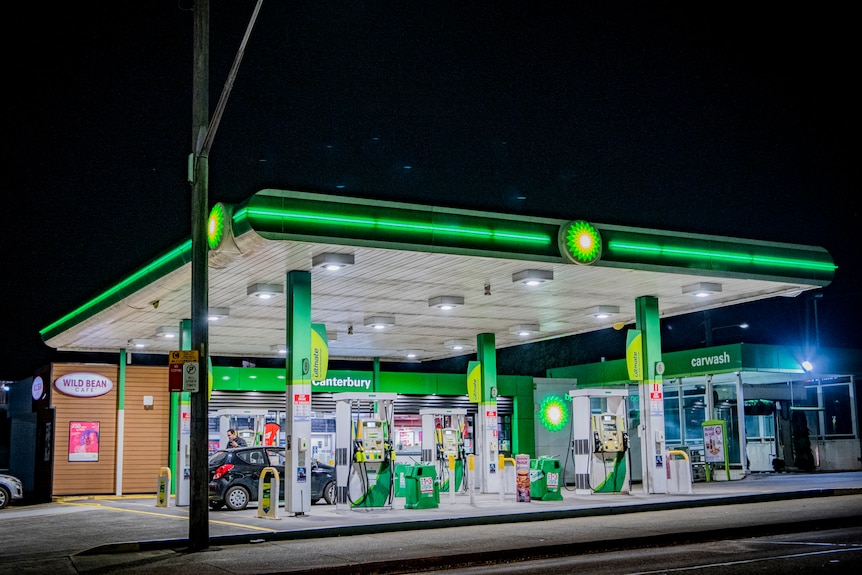 A petrol station at night, with bright white lighting and neon green and yellow BP branding