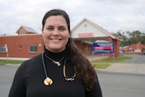 A woman with a stethoscope in front of a hospital