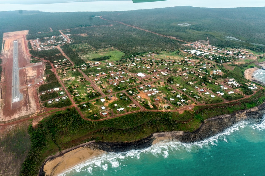 An aerial photograph of a small community on a green island surrounded by turquoise water.