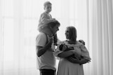 A black and white photo of a young family, a man, woman and two kids