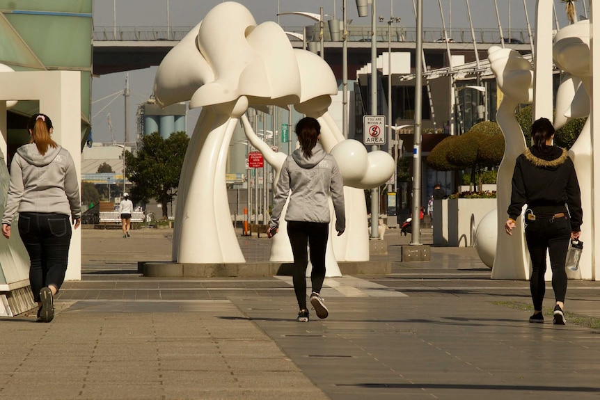Three women walking in Docklands at least 1.5 metres apart.