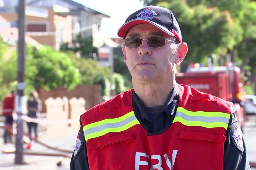 A man in a red fire rescue victoria vest, hat and sunglasses