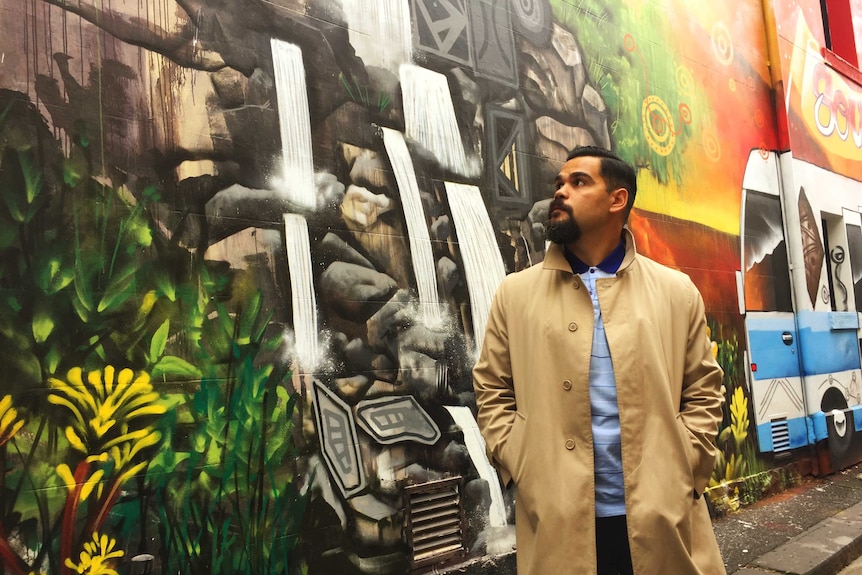 Artist Robert Young stands in front of his mural in Fitzroy.