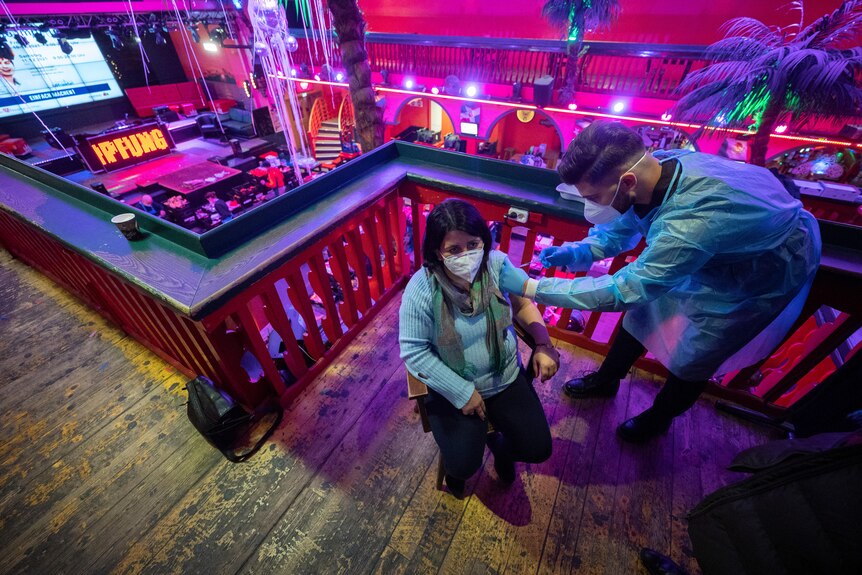 A woman recieves a COVID vaccine at an open vaccination event in a music club.