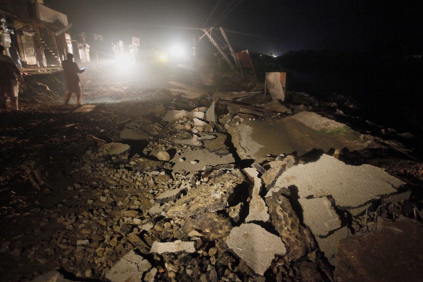 A large pile of rubble and rocks is seen on the ground during night time