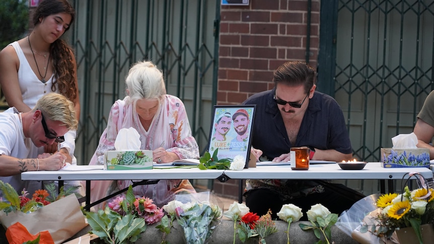 People sign condolence book at a vigil for luke baird and jesse davies