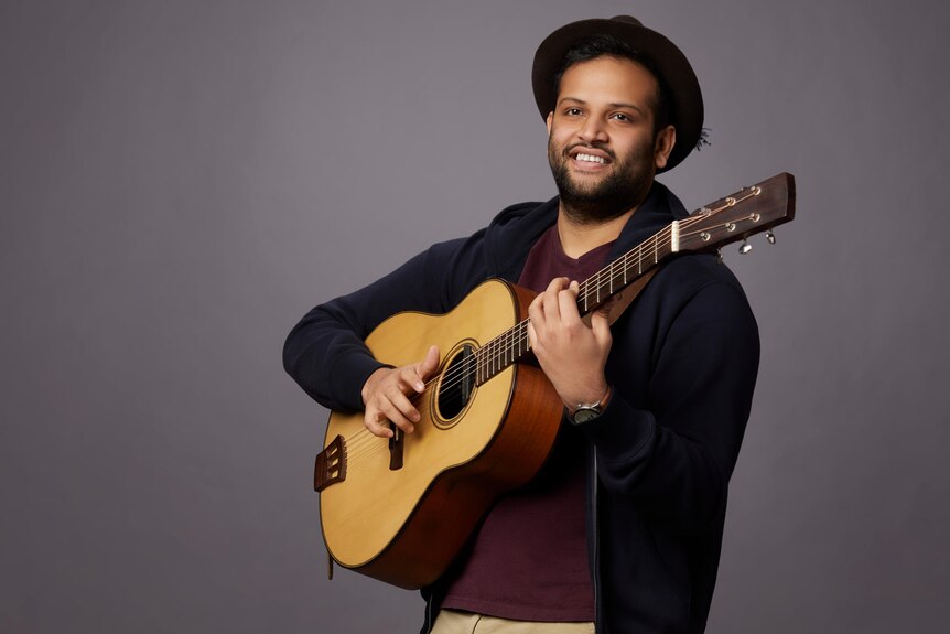 An Indian man holding a guitar