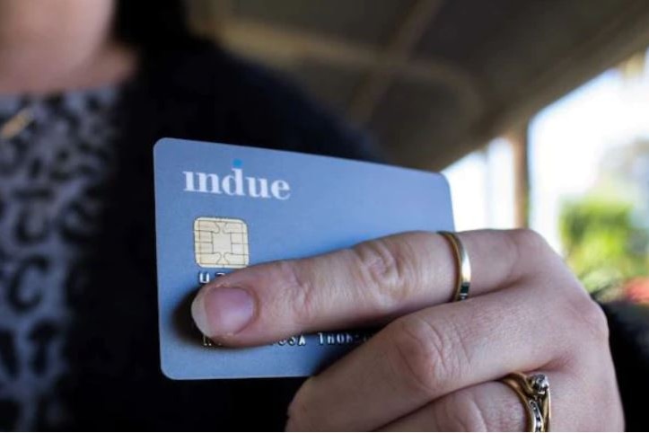 w woman holding a blue debit card with two gold rings.