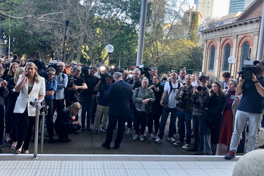 Large group of journalist and camera crews standing outside court.