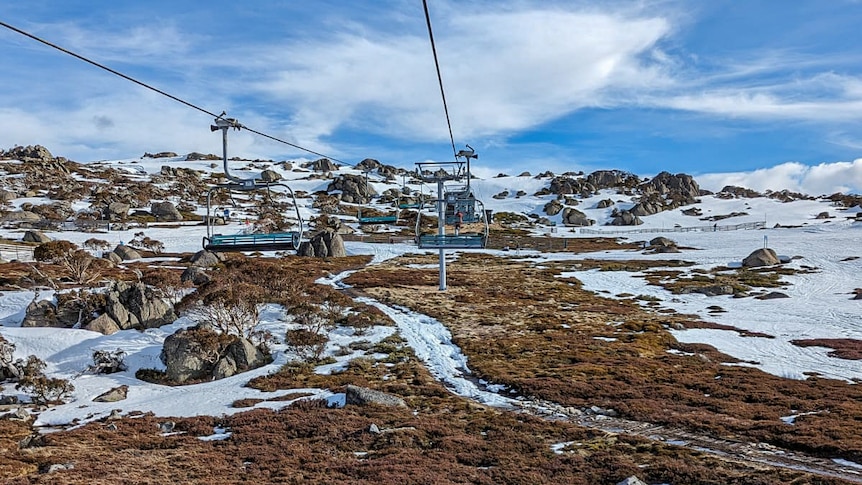 Patchy snow partially covers the ground at a ski resort.