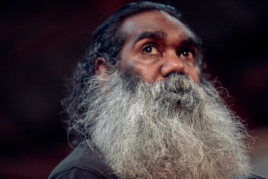 A man with a beard looks up.