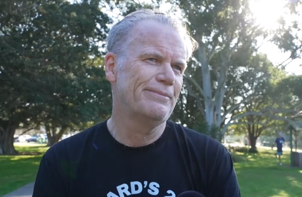 Photo of a man in a black t-shirt looking off to his left side. 
