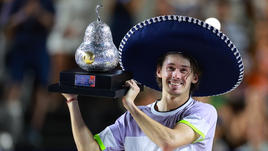 Alex de Minaur holds a trophy and wears a sombrero