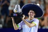 Alex de Minaur holds a trophy and wears a sombrero