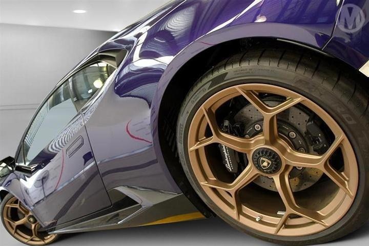 A purple Lamborghini with gold rims.