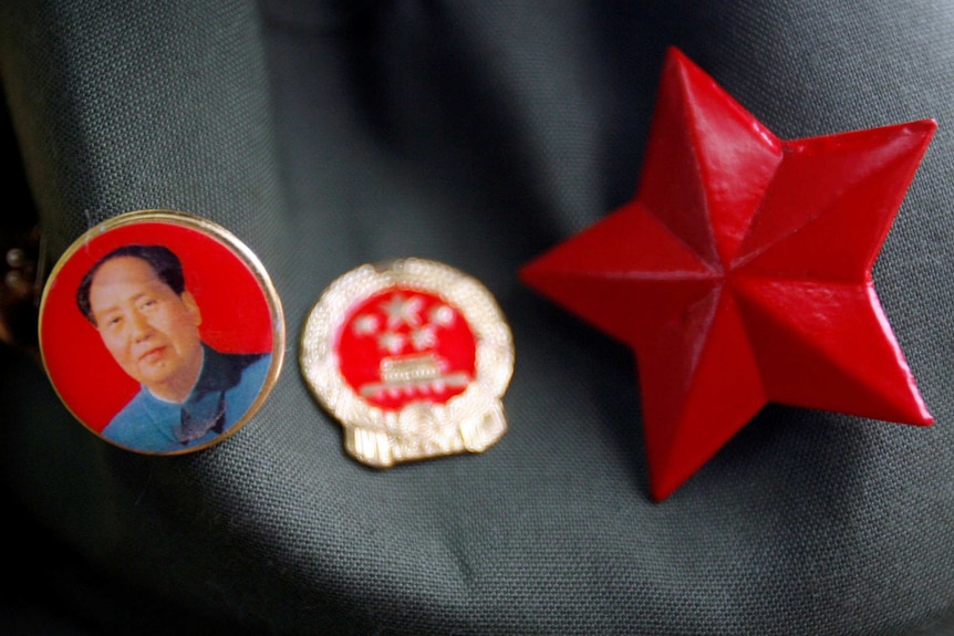 A badge bearing the portrait of Mao Zedong can be seen next to a Chinese Communist Party badge and a red star.