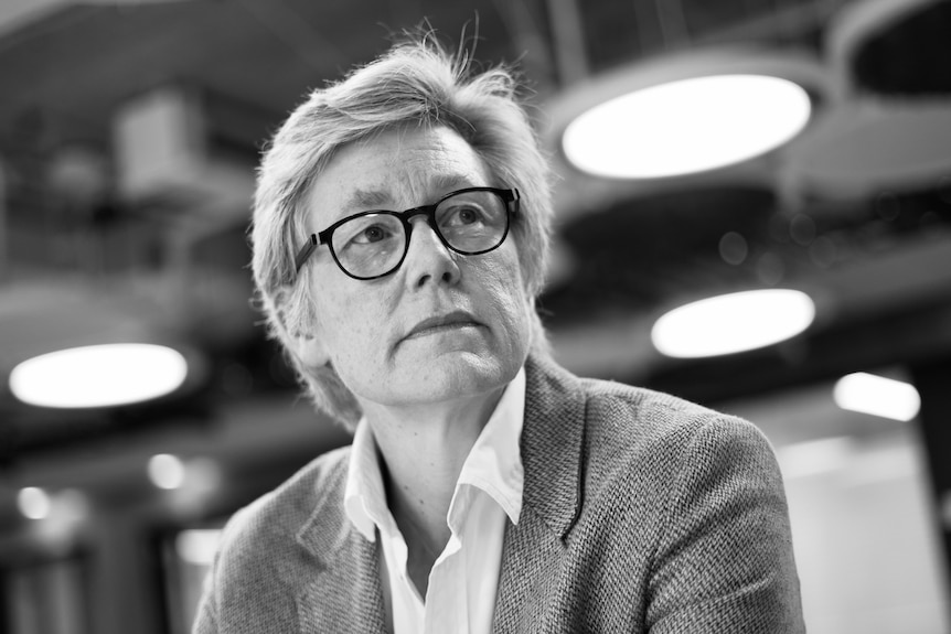 ஒரு நடுத்தர வயதுப் பெண் சிந்தனையுடன் பக்கவாட்டில் பார்க்கும் கருப்பு வெள்ளை புகைப்படம்.