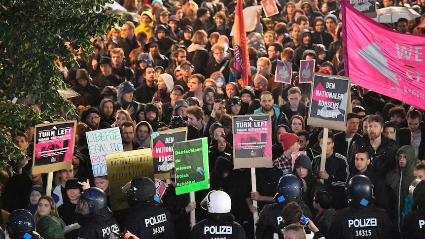 Police stop protesters, who are holding signs.