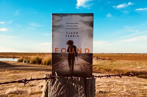 Book sitting on a fence post in a rural farm setting