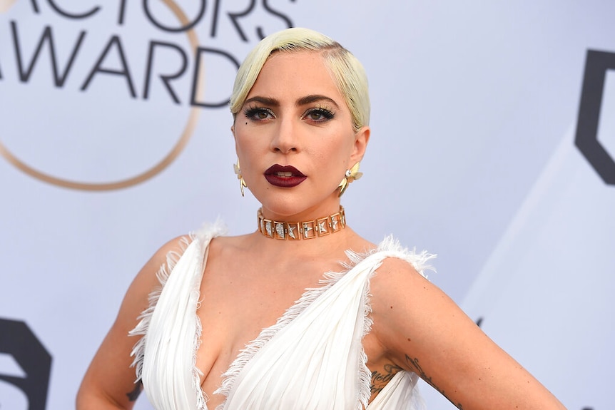 Lady Gaga wearing a white gown with frayed edges and a dark red lipstick.