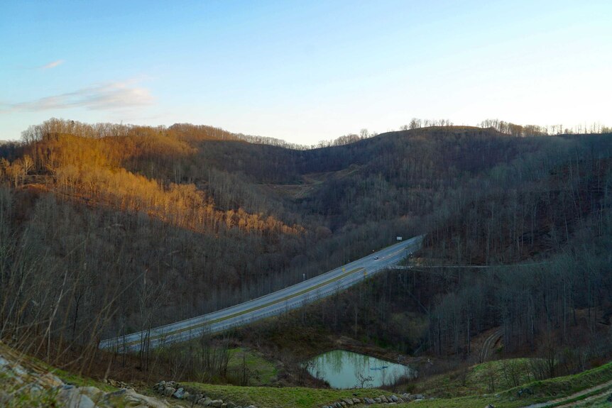 A highway runs through the rolling hills of the Appalachia mountain region in West Virgina at dusk