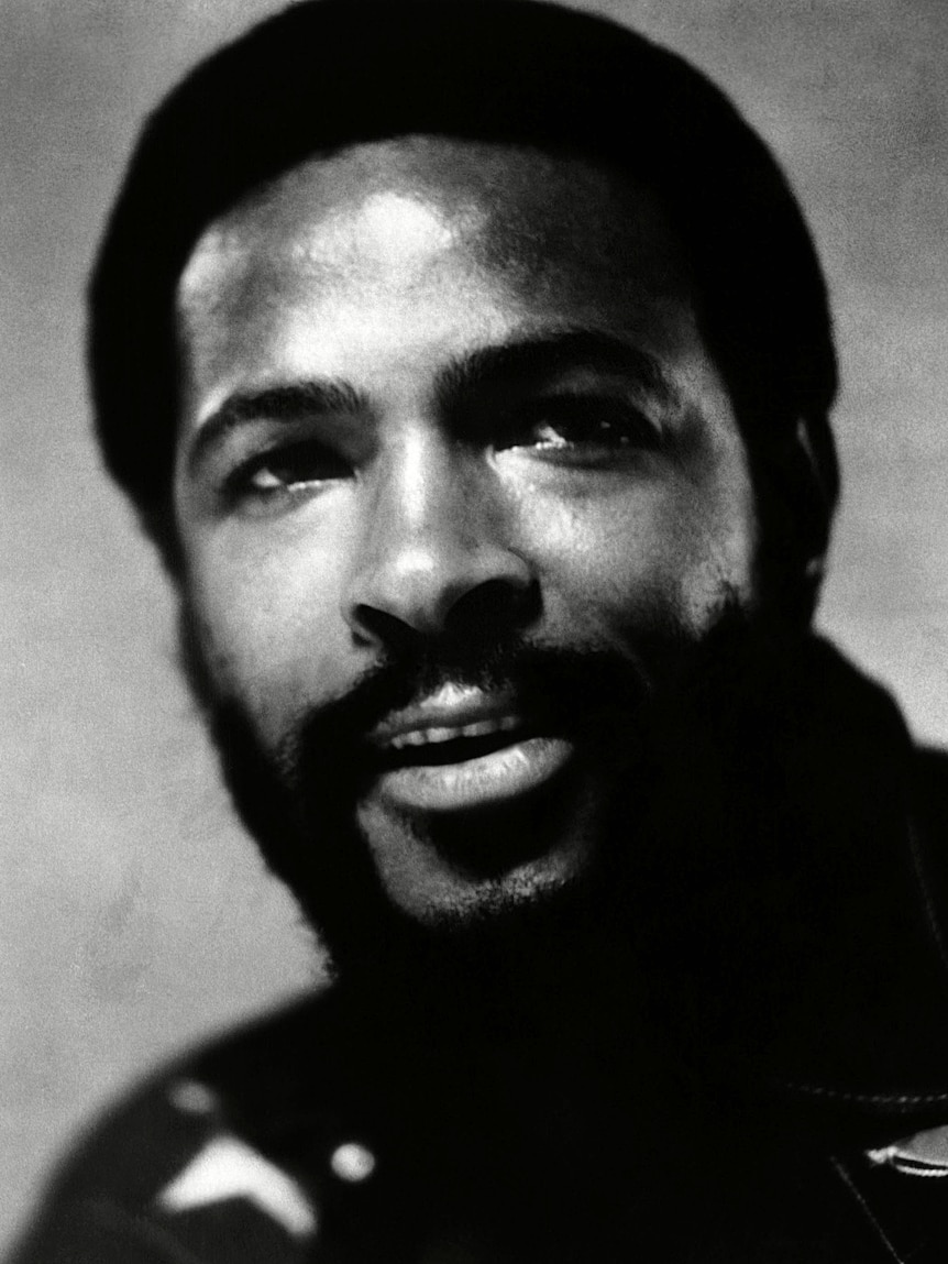 A black and white 70s photo of a Black man, Marvin Gaye, he looks up with a small smile