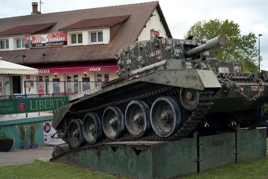 A British tank sits in front of “3 Gliders Snack bar” and “Liberty” souvenir store