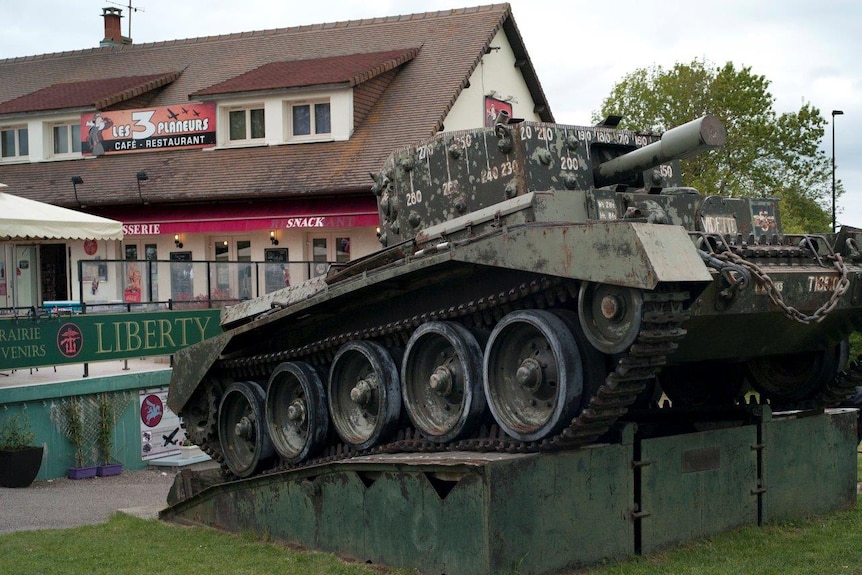 A British tank sits in front of “3 Gliders Snack bar” and “Liberty” souvenir store