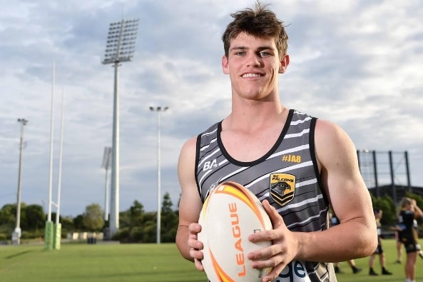 young man holds rugby league ball on field