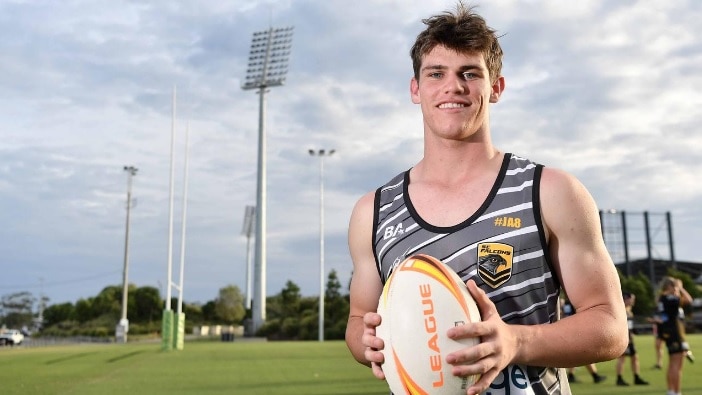 young man holds rugby league ball on field