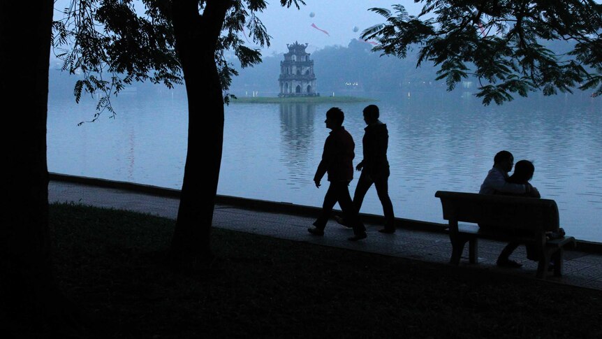 A couple in shadow walk past a park