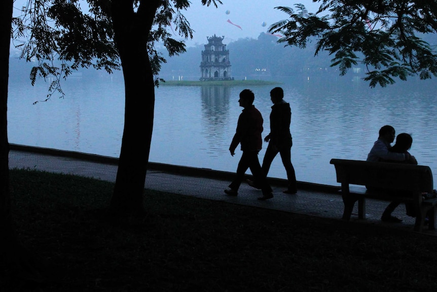 A couple in shadow walk past a park
