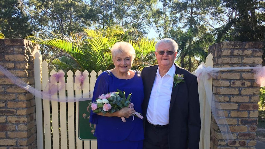 Pam and Ron Sinclair after getting married standing in front of a gate.