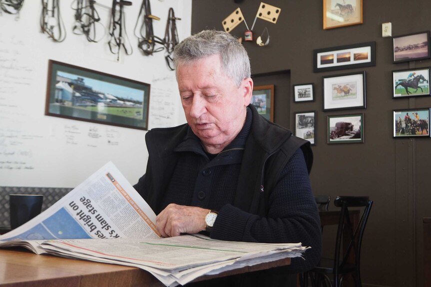 A man sitting down reads the newspaper.
