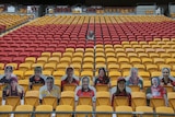 Cut out pictures of fans and Wally Lewis fill empty seats in a stadium.