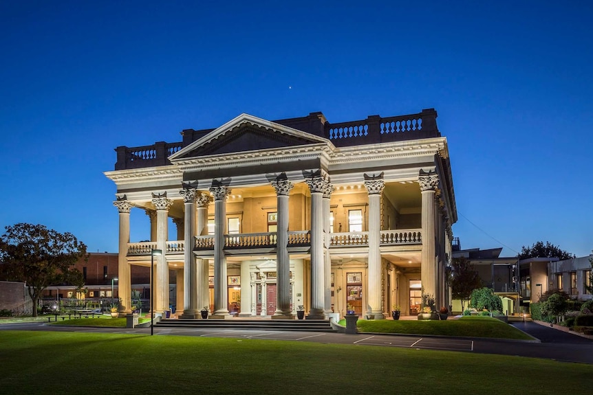 At dusk, you view an ornate classical manor home sitting in the middle of a school yard.