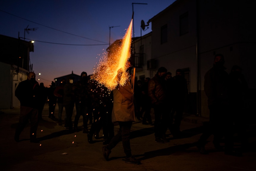 En la oscuridad cercana, una de las figuras enciende los fuegos artificiales.