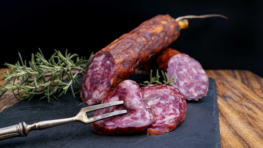 A plate with slices of salami and sprigs of rosemary on it