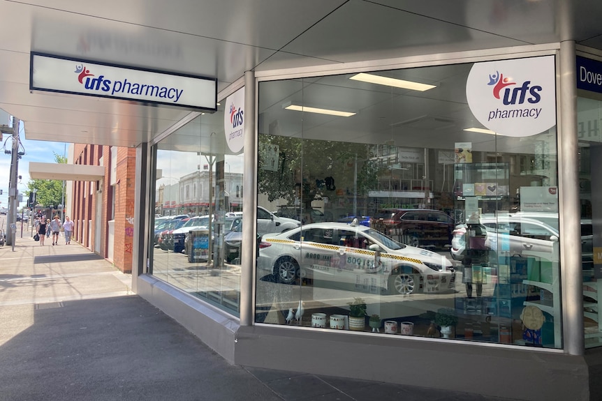 A pharmacy shop front window with the pharmacy's name on a sign