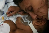 A close up shot of a mother cuddling her girl on a hospital bed.