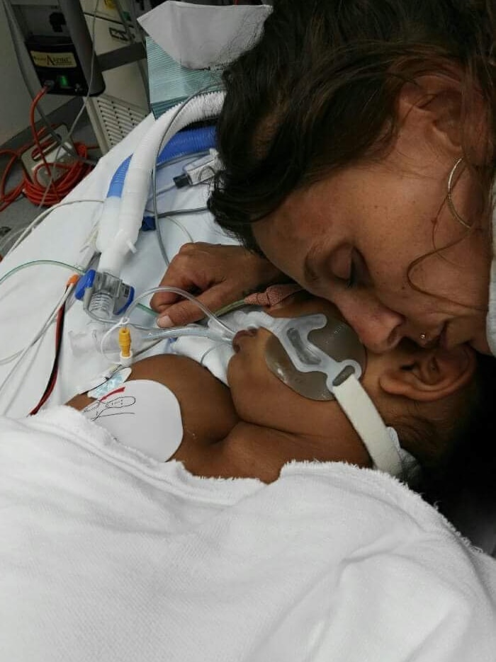 A close up shot of a mother cuddling her girl on a hospital bed.