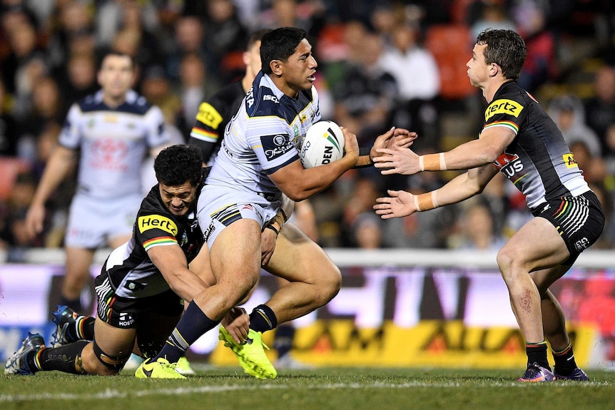 Jason Taumalolo carries the ball while being tackled by the Penrith defence.