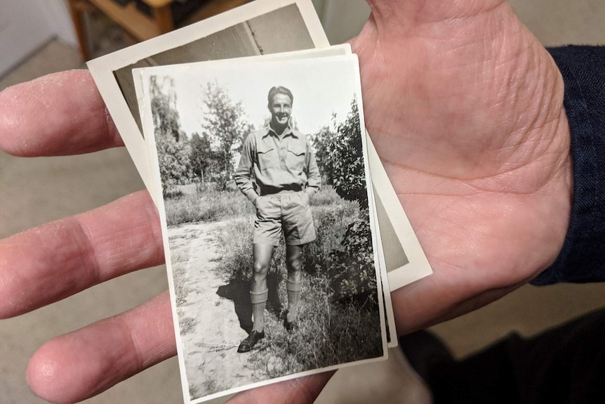 A black and white photo of Frank Sims smiling with his hands in his shorts pockets.