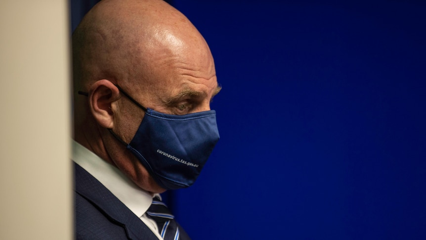 A side-on profile of the Premier wearing a mask in front of a blue background.