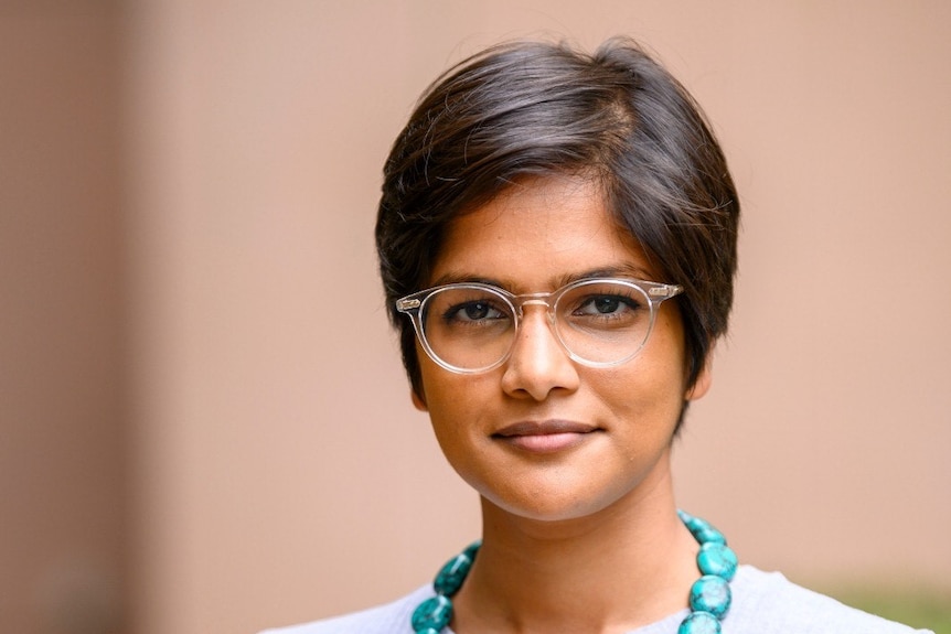 A woman in a blue necklace in a blue jumper