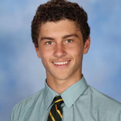 A young boy from the shoulder up, smiling at the camera. 